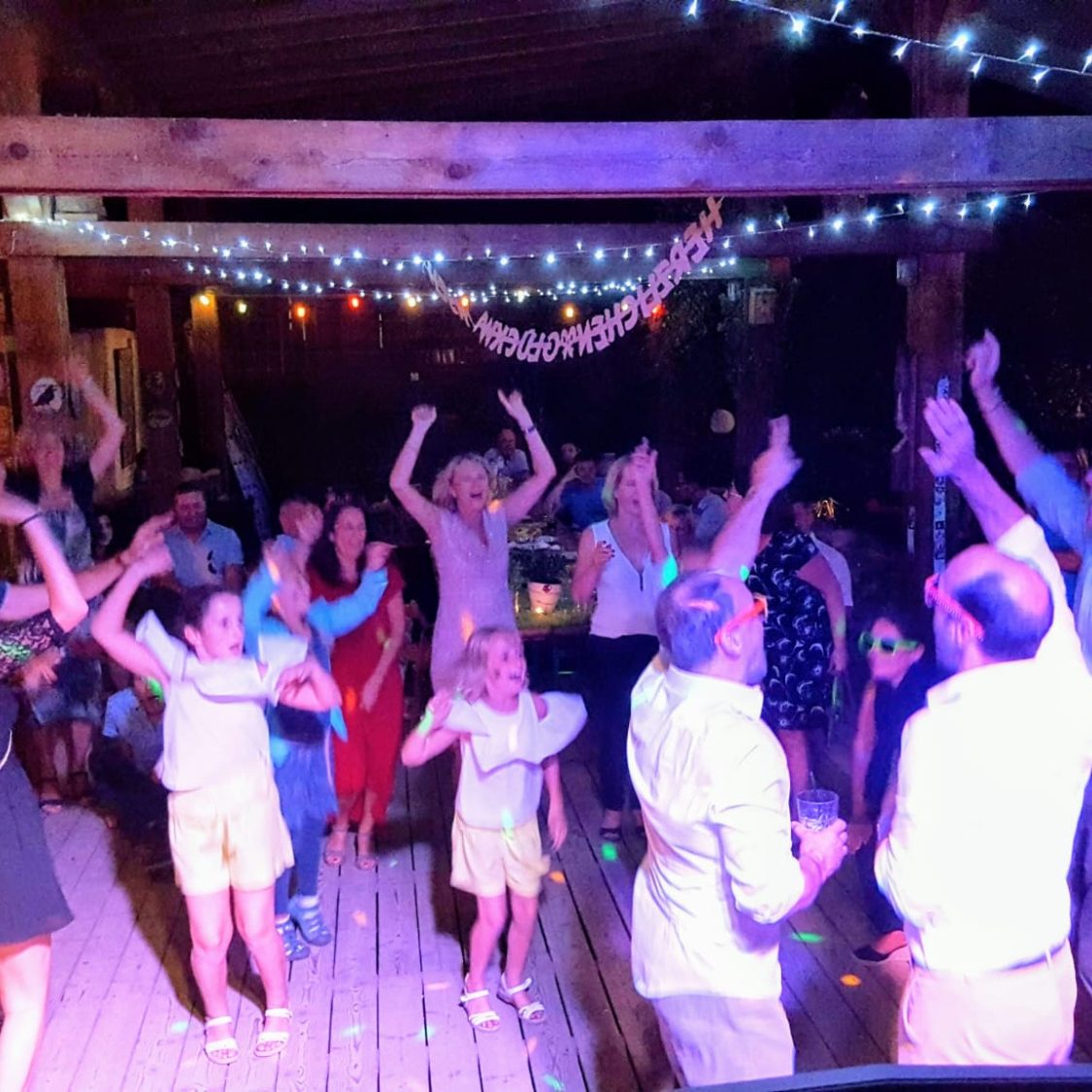 Menschen tanzen und feiern auf einer bunten Party mit Lichtern und Musik.