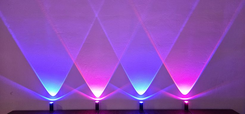 Bunte Lichtstrahlen in Blau und Lila, die diagonal über eine Oberfläche verbreitet sind.