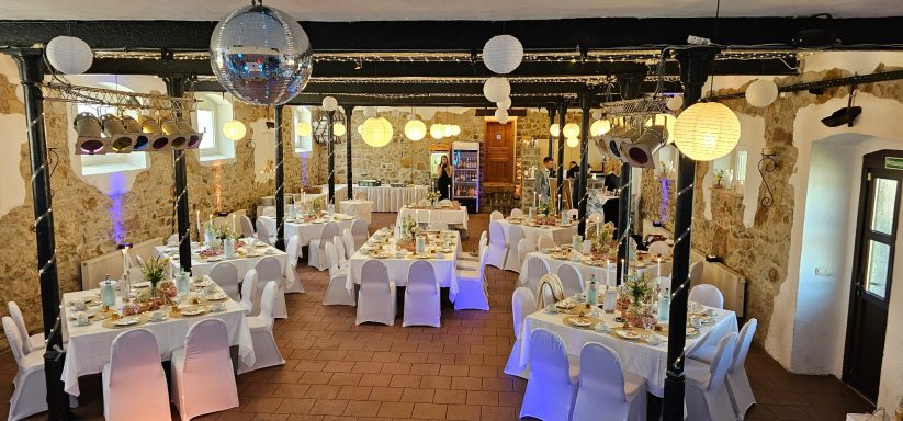 Eleganter Veranstaltungsraum mit Tischen, Stühlen und festlicher Beleuchtung.
