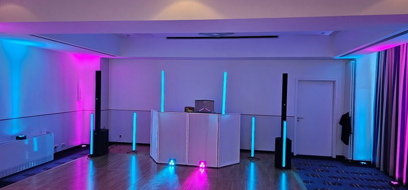 Moderne DJ-Ausrüstung in einem Raum mit pinken und blauen Lichteffekten.