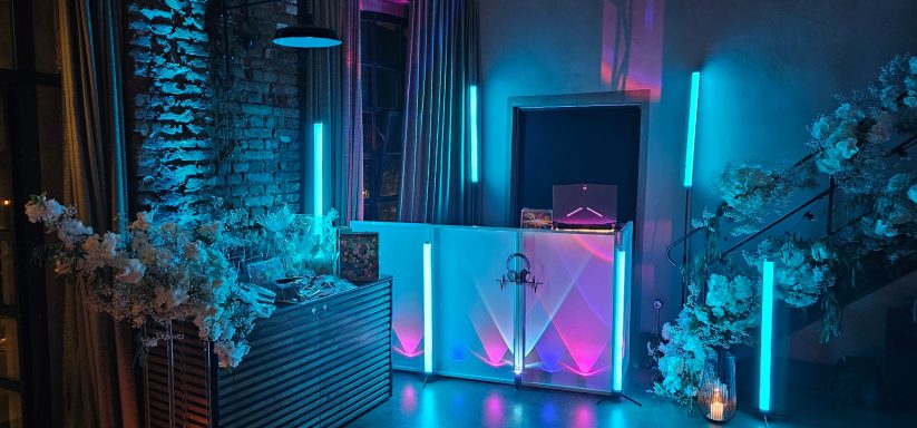 Räumlichkeit mit blauen und lila LED-Leuchten, dekoriert mit Blumenarrangements.