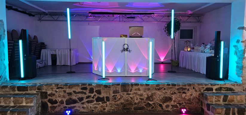 Eventlocation mit DJ-Pult, Lichtern in Blau und Pink sowie Tischen im Hintergrund.