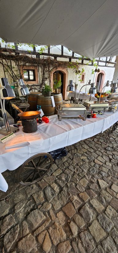 Dekorierter Tisch mit verschiedenen Speisen und Getränken unter einem Zelt.