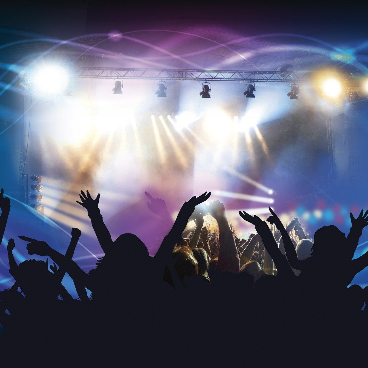 Jubelnde, feiernde  Menschen bei einem Konzert oder DJ Event mit bunten Lichteffekten und Nebel.